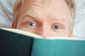 Caucasian young emotional cheerful man reading a book while lying down.