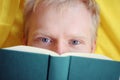 Caucasian young emotional cheerful man reading a book while lying down.