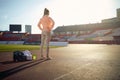 Caucasian young female standing at the athletic track with hands on hips, preparing for training, visualizing goal