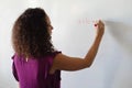Caucasian young female teacher writing formula on whiteboard during math class in school Royalty Free Stock Photo