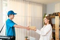 Caucasian young girl shopping online and receive order from delivery man in blue uniform with cooler bag at the apartment Royalty Free Stock Photo