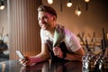 Smiling waiter using his cellphone in romantic cafe