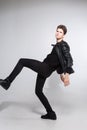 Caucasian young guy posing in studio, full-length portrait of a model in black clothes. Handsome teenager in a black jacket, jeans Royalty Free Stock Photo