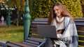 Caucasian young lady businesswoman student sit on bench in park chatting online by laptop video call conference Royalty Free Stock Photo