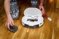 Caucasian young man in christmas pajamas doing vacuum cleaner robot maintenance. Male in winter patterned sleepwear and red socks Royalty Free Stock Photo