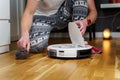 Caucasian young man in christmas pajamas doing vacuum cleaner robot maintenance. Male in winter patterned sleepwear and red socks Royalty Free Stock Photo