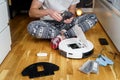 Caucasian young man in christmas pajamas doing vacuum cleaner robot maintenance. Male in winter patterned sleepwear and red socks Royalty Free Stock Photo