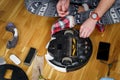 Caucasian young man in christmas pajamas doing vacuum cleaner robot maintenance. Male in winter patterned sleepwear and red socks Royalty Free Stock Photo