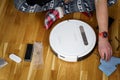 Caucasian young man in christmas pajamas doing vacuum cleaner robot maintenance. Male in winter patterned sleepwear and red socks Royalty Free Stock Photo