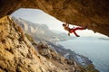 Young man climbing challenging route in cave against beautiful view of coast Royalty Free Stock Photo