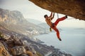 Young man climbing challenging route in cave against beautiful view of coast Royalty Free Stock Photo