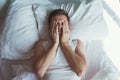 Caucasian young man closed eyes with hands in bed Royalty Free Stock Photo