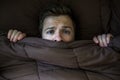 Caucasian young man hiding in bed under the blanket at home. Royalty Free Stock Photo