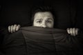 Caucasian young man hiding in bed under the blanket at home. Royalty Free Stock Photo