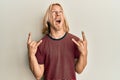 Caucasian young man with long hair doing rock gesture angry and mad screaming frustrated and furious, shouting with anger looking Royalty Free Stock Photo