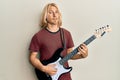 Caucasian young man with long hair playing electric guitar clueless and confused expression Royalty Free Stock Photo