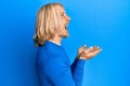 Caucasian young man with long hair presenting with open palms, holding something angry and mad screaming frustrated and furious, Royalty Free Stock Photo