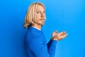 Caucasian young man with long hair presenting with open palms, holding something relaxed with serious expression on face Royalty Free Stock Photo