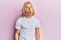 Caucasian young man with long hair wearing casual white t shirt afraid and shocked with surprise expression, fear and excited face Royalty Free Stock Photo