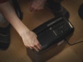 Caucasian young man is pressing the button to destroy important documents in a black shredder Royalty Free Stock Photo