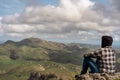 Caucasian young man sitting at the top of the mountain and contemplating the landscape Royalty Free Stock Photo