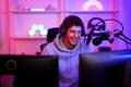 Caucasian young streamer boy happy smile while review game e-sport trendy with computer foreground in neon violet room