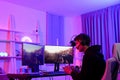 Caucasian young streamer man playing shooter game and battle with his online friend in violet neon light room