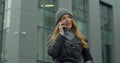 Caucasian young stylish redhead woman talking on cellphone in the morning at street. Beautiful happy female speaking on Royalty Free Stock Photo