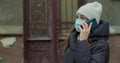 Caucasian young stylish woman in medical protective mask talking on cellphone in the street. Beautiful happy female Royalty Free Stock Photo