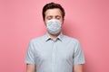 Caucasian young unemotional man wearing medical mask standing with closed eyes