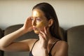 Caucasian young woman applying moisturizing or peeling golden facial mask and touch her face with hands. Side view. Royalty Free Stock Photo