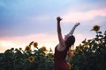 Caucasian young woman with arms raised enjoying her freedom in sunflower field during sunset Royalty Free Stock Photo