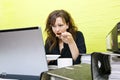 Caucasian young woman eating and working on her laptop computer at her desk