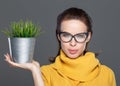 Caucasian woman in eyeglasses holding indoor plant in metal pot