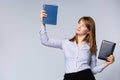 Caucasian young woman in gray shirt holding up two books. Portrait of smiling businesswoman, teacher or university student, Royalty Free Stock Photo