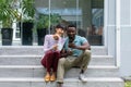 Caucasian young woman looking at african american boyfriend using smart phone on steps outside house Royalty Free Stock Photo
