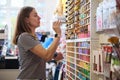 Caucasian young woman merchandiser, seller stacking pencils on shelves in school stationery store. Office supply shop