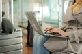 Caucasian young woman sitting in waiting room with laptop near valise. Royalty Free Stock Photo