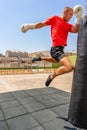 Caucasian youong man hitting a punching bag with his knee while training doing kikcboxing. Take a spectacular leap to Royalty Free Stock Photo