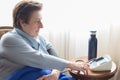 Caucasic woman over 70 checking her blood pressure at home with a digital monitor. Short hair blue sweater