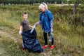 Caucasoid people put empty plastic bottles in a big black garbage bag. volunteers. grandmother and grandson