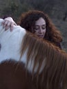 Caucassian female forming bond with a piebald mare on an autumn day.