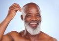 Caught up with cosmetics. Studio portrait of a mature man applying serum to his face against a blue background. Royalty Free Stock Photo