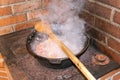 Cauldron with boiling food in heavy smoke.