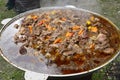 Cauldron full of stewed delicious meat set on moveable wood stove