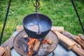 A cauldron with a piece of meat in broth boiling on fire. Pot of soup on a summer day, camping