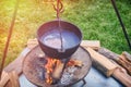 A cauldron with a piece of meat in broth boiling on fire. Pot of soup on a summer day, lifestyle