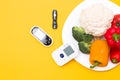 cauliflower, broccoli and pepper on a white plate, on a yellow background glucose meter and blood pressure monitor is leaned on a Royalty Free Stock Photo