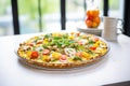 cauliflower pizza loaded with veggies on a glass table, natural light