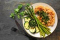 Cauliflower steak with grilled vegetables, top view scene on dark background